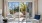 a room with a glass door and a patio with chairs and a view of trees