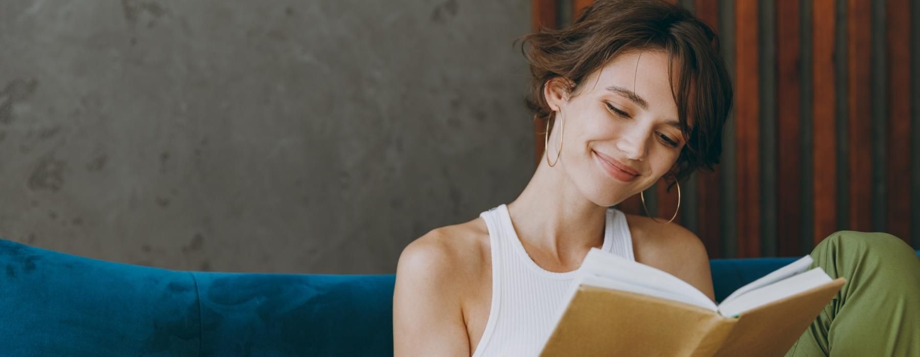 a woman sitting on a couch reading a book